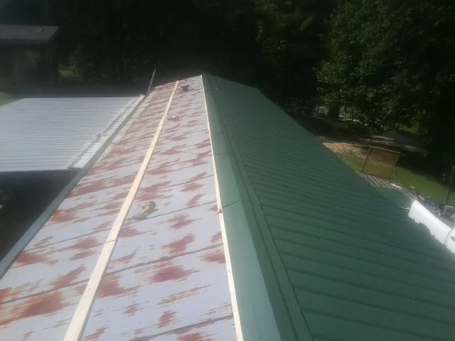 Old rusted panels beside newly installed green metal roofing — Wind Damage Roof Repair by Roofing Brothers in Stafford