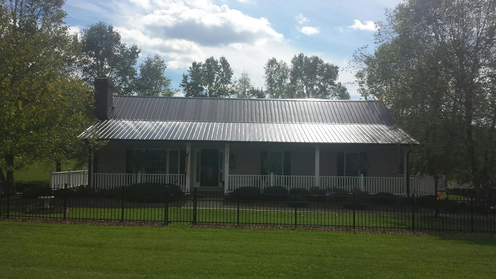 Gray metal roof on a brick ranch with a full width front porch — Gutter Guard Installation work by our crew in Stafford