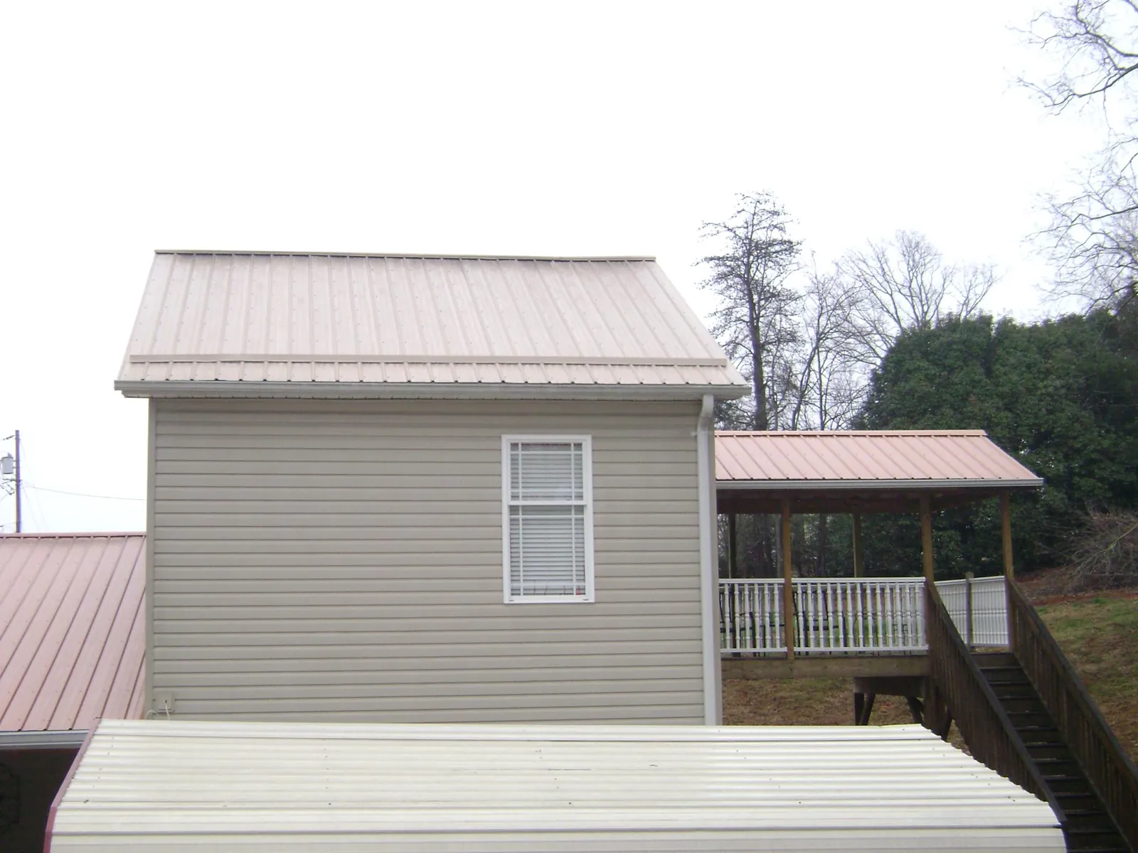 Tan metal roofs on a two story addition and attached porch, from a Roof Replacement job in Stafford