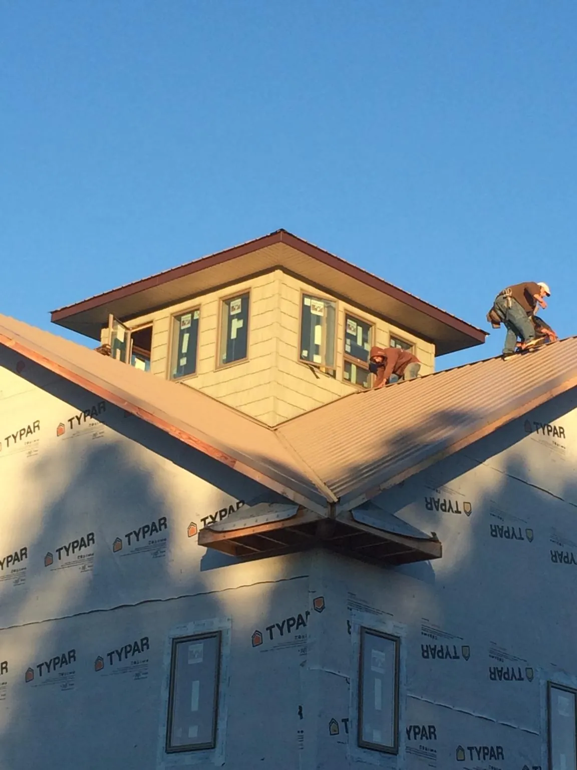 Roofers working around a rooftop cupola on a new metal roof at sunset — Roof Waterproofing in Stafford by Roofing Brothers